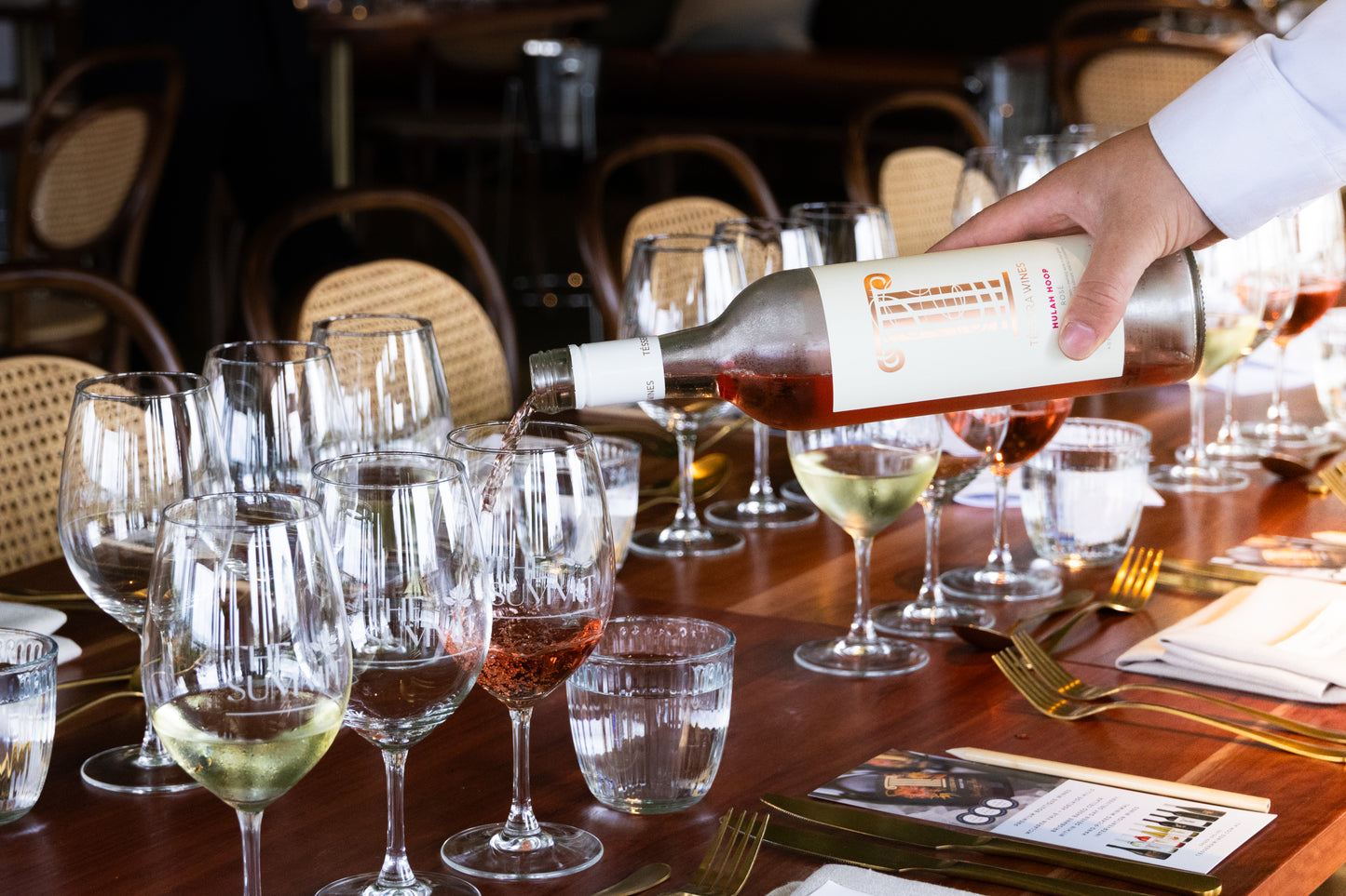 A bottle of Tessera Wines Hulah Hoop Rosé, one of Queensland’s best rosé wines, being poured into glasses at an elegantly set dining table during a wine event at The Summit Restaurant